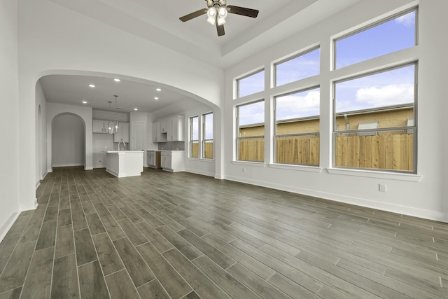 10403 Shining Dawn Way, Richmond, TX 77406 - unfurnished living room with ceiling fan, arched walkways, dark wood-type flooring, and recessed lighting