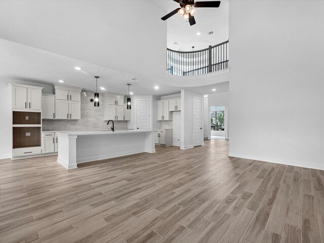 3193 Stingray Cove Dr, Katy, TX 77493 - unfurnished living room with a ceiling fan, light wood-style floors, a towering ceiling, and recessed lighting