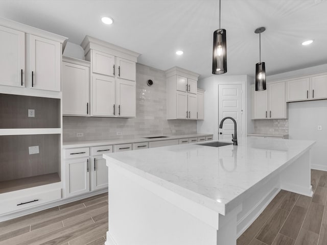3193 Stingray Cove Dr, Katy, TX 77493 - kitchen featuring light wood finished floors, a kitchen island with sink, backsplash, recessed lighting, and pendant lighting