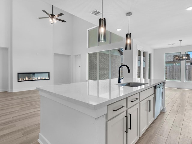 3193 Stingray Cove Dr, Katy, TX 77493 - kitchen featuring light wood finished floors, dishwasher, white cabinets, hanging light fixtures, and a kitchen island with sink