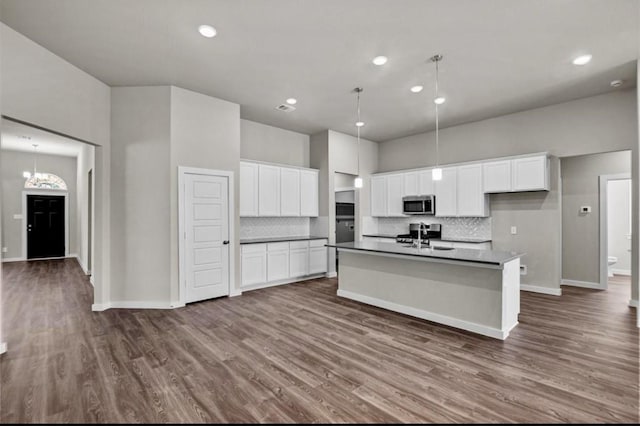 716 Ivory Creek Ct, Willis, TX 77378 - kitchen featuring decorative backsplash, dark countertops, stainless steel microwave, white cabinets, and a sink