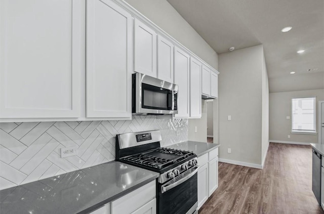 716 Ivory Creek Ct, Willis, TX 77378 - kitchen with wood finished floors, baseboards, white cabinets, tasteful backsplash, and appliances with stainless steel finishes