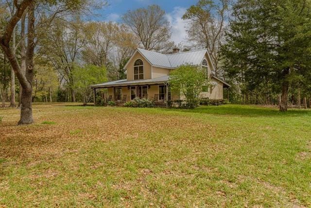 exterior space with covered porch, metal roof, and a front yard