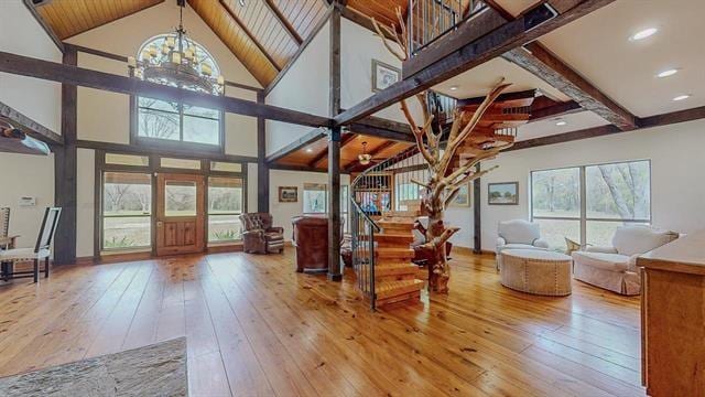 living room featuring high vaulted ceiling, hardwood / wood-style flooring, a chandelier, and stairs