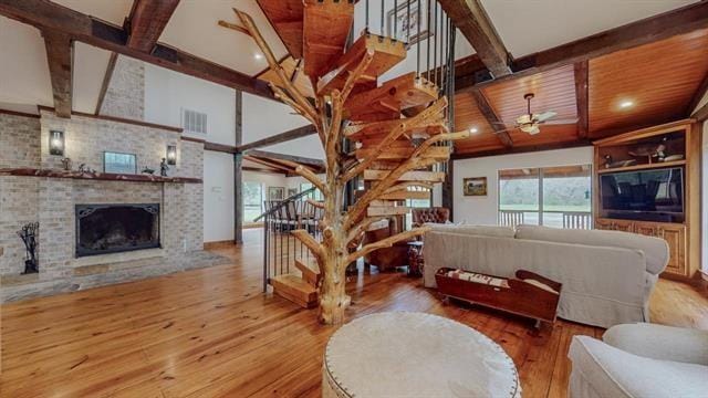 living room featuring stairway, wood ceiling, visible vents, a brick fireplace, and wood finished floors