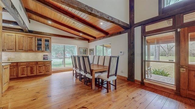 dining room featuring wooden ceiling, vaulted ceiling with beams, baseboards, and light wood-type flooring