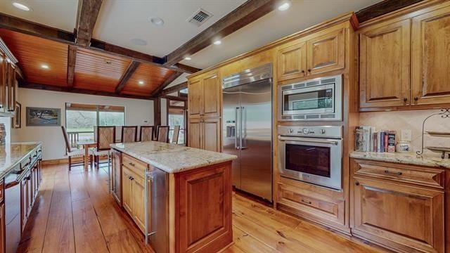 kitchen with light wood-style floors, a center island, built in appliances, and visible vents
