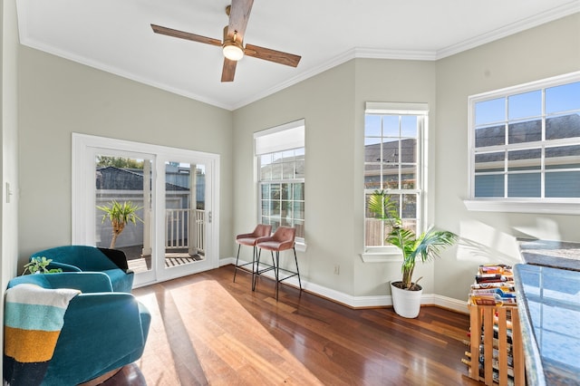 living area featuring a ceiling fan, ornamental molding, baseboards, and wood finished floors