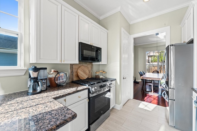 kitchen with crown molding, baseboards, dark stone counters, appliances with stainless steel finishes, and white cabinetry