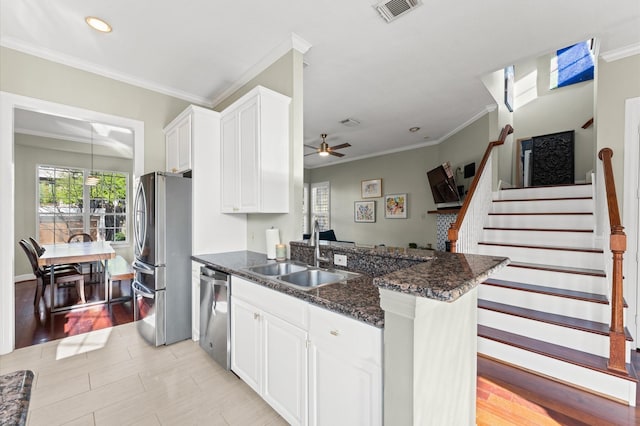 kitchen featuring crown molding, a sink, appliances with stainless steel finishes, a peninsula, and visible vents