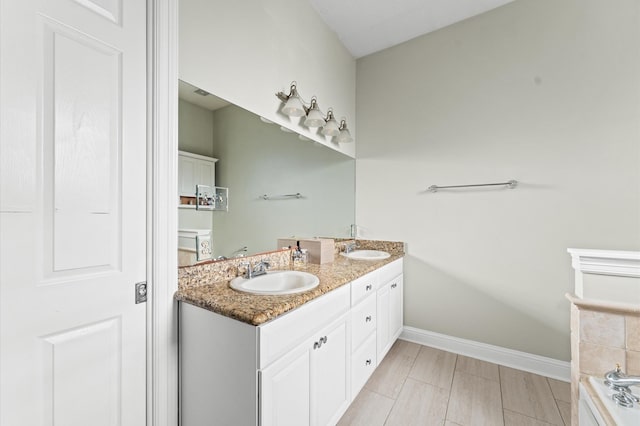 full bath featuring baseboards, double vanity, a sink, and a bathtub