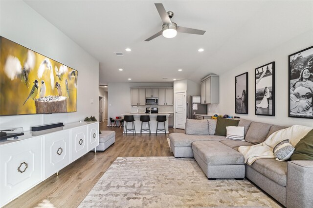 living room with light wood-style flooring, visible vents, ceiling fan, and recessed lighting