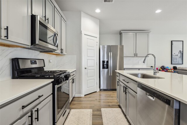 kitchen with light wood-style flooring, a sink, appliances with stainless steel finishes, and gray cabinets
