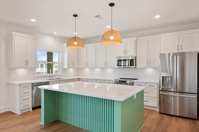 kitchen featuring white cabinets, appliances with stainless steel finishes, light wood-style flooring, and a sink