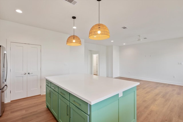 kitchen featuring green cabinetry, visible vents, a center island, light wood-type flooring, and stainless steel fridge