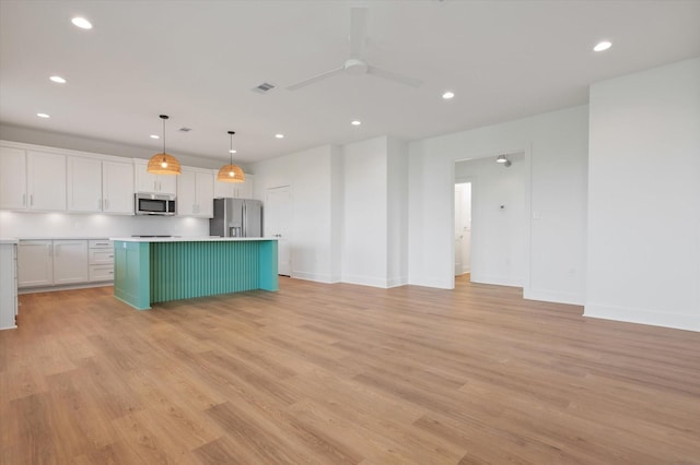kitchen featuring recessed lighting, light wood-style flooring, a kitchen island, white cabinetry, and appliances with stainless steel finishes