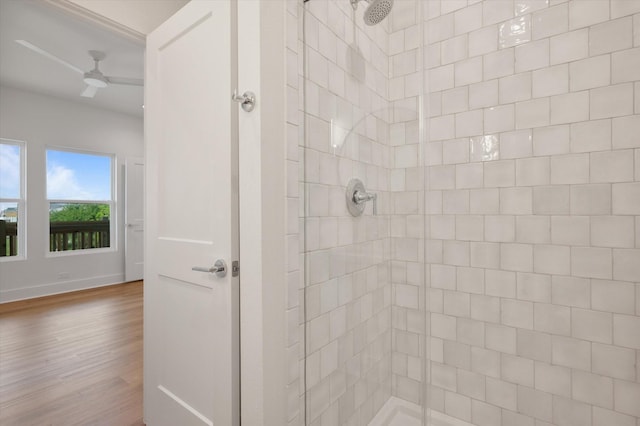 full bath with a tile shower, ceiling fan, wood finished floors, and baseboards