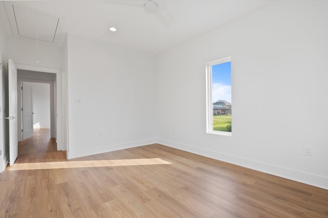 unfurnished room featuring attic access, baseboards, and light wood-style floors