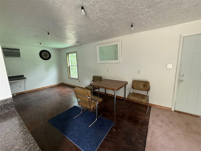 living area with baseboards, a textured ceiling, and an AC wall unit