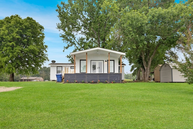 manufactured / mobile home with a storage unit, french doors, an outdoor structure, and a front yard