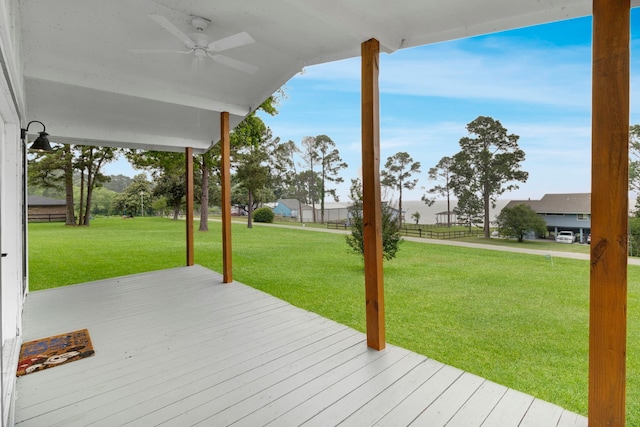 wooden deck with a lawn and a ceiling fan