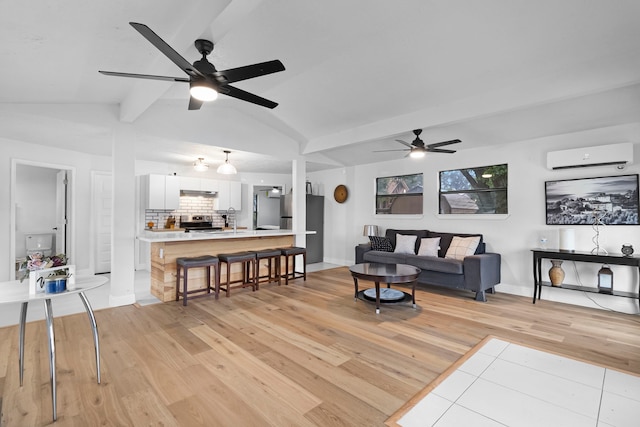 living room featuring vaulted ceiling with beams, a wall mounted air conditioner, ceiling fan, light wood finished floors, and baseboards