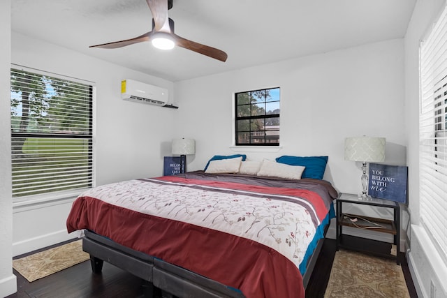 bedroom with a ceiling fan, multiple windows, a wall unit AC, and wood finished floors