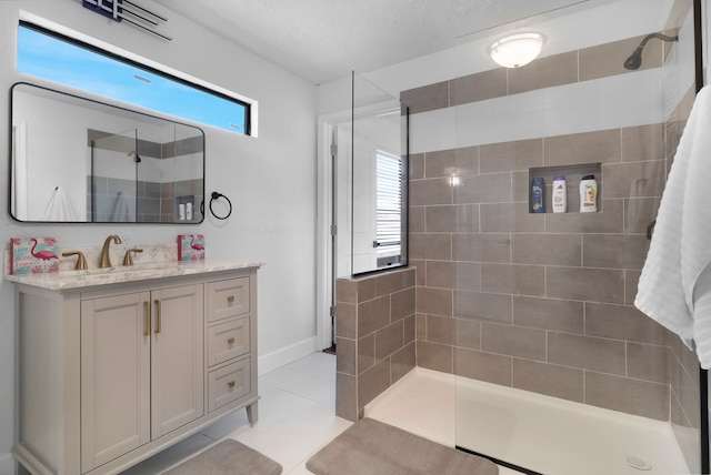 full bathroom with vanity, baseboards, tile patterned flooring, and tiled shower