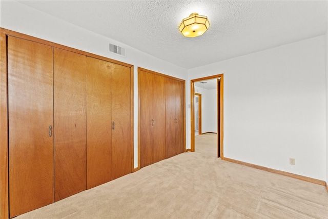 1403 Marlock Ln, Pasadena, TX 77502 - unfurnished bedroom with multiple closets, carpet floors, a textured ceiling, and baseboards