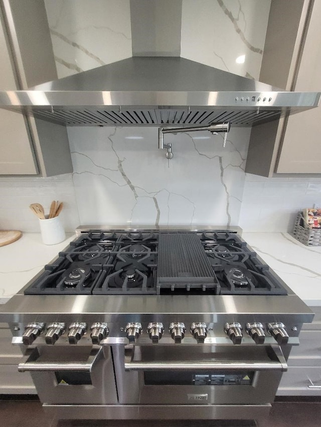18602 Carriage Ct, Houston, TX 77058 - kitchen view of extractor fan, tasteful backsplash, stainless steel stove, and light stone counters