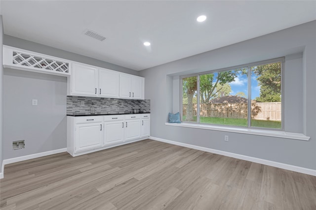 1410 Wesley Ln, Deer Park, TX 77536 - kitchen with dark countertops, light wood-style floors, backsplash, white cabinetry, and baseboards