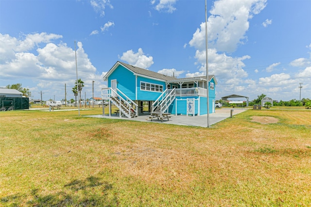 back of property featuring a yard, stairway, a patio area, and a detached carport