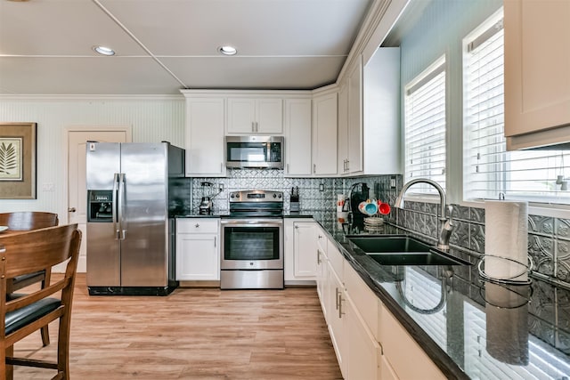 kitchen featuring decorative backsplash, a sink, white cabinetry, and appliances with stainless steel finishes