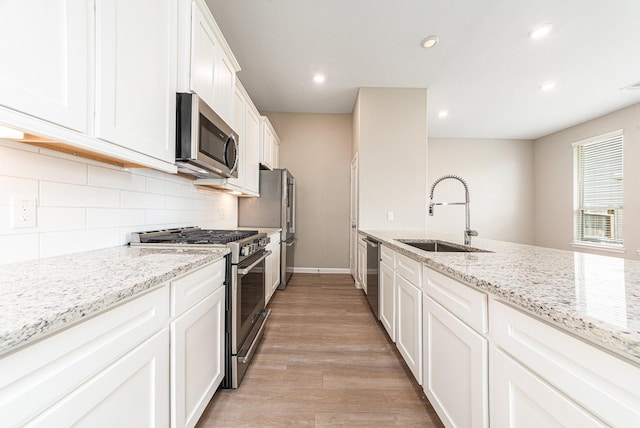 210 Fulton Station Dr, Houston, TX 77009 - kitchen with light stone countertops, light wood-type flooring, a sink, stainless steel appliances, and backsplash