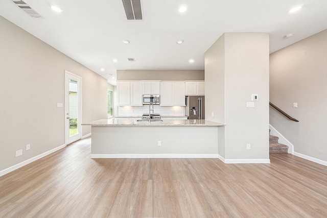 210 Fulton Station Dr, Houston, TX 77009 - kitchen with visible vents, light wood-style floors, white cabinetry, stainless steel appliances, and decorative backsplash