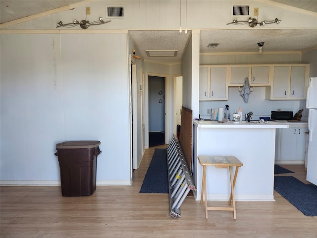 kitchen with black microwave, light wood finished floors, and visible vents