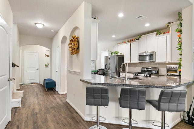 13754 Evansdale Ln, Houston, TX 77083 - kitchen with appliances with stainless steel finishes, a sink, arched walkways, dark stone countertops, and recessed lighting