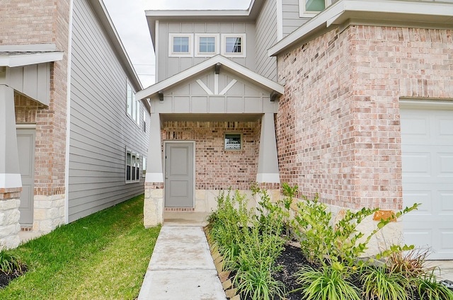 entrance to property with board and batten siding, brick siding, and a garage