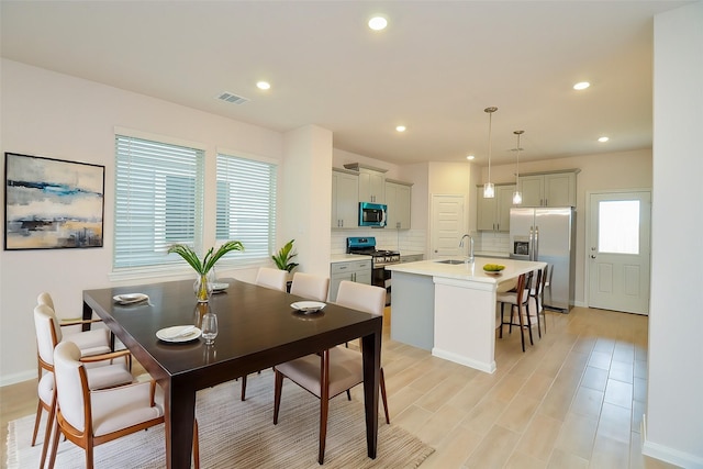 dining space featuring baseboards, visible vents, light wood-style floors, and recessed lighting