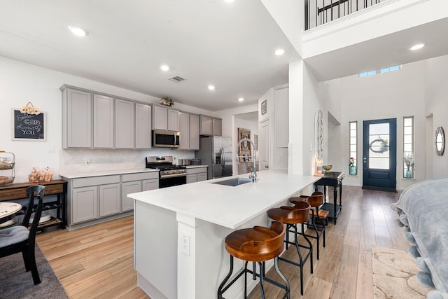 kitchen with stainless steel appliances, gray cabinets, a sink, recessed lighting, and a high ceiling