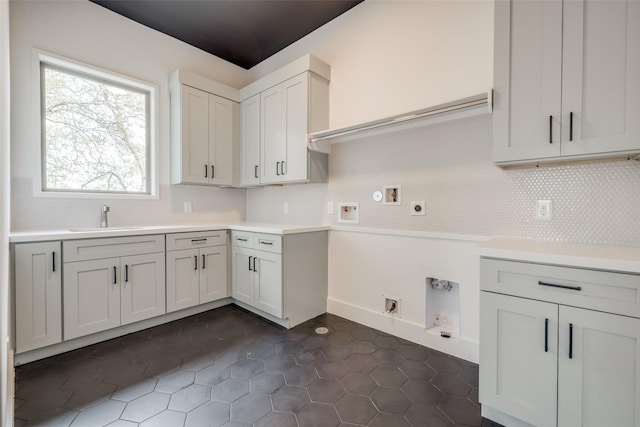 kitchen featuring backsplash, light countertops, dark tile patterned flooring, and a sink