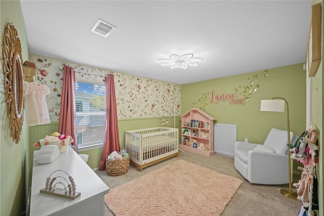 30208 Arnold Branch Dr, Magnolia, TX 77355 - bedroom with visible vents, a nursery area, wainscoting, carpet floors, and wallpapered walls