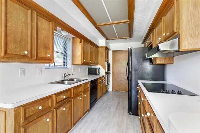 16002 Castaway Ct, Crosby, TX 77532 - kitchen featuring a sink, black appliances, under cabinet range hood, light wood-style floors, and brown cabinetry