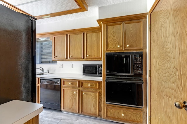 16002 Castaway Ct, Crosby, TX 77532 - kitchen with black appliances, light countertops, light wood-style flooring, and a sink