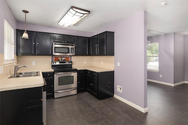 18911 Brownstone Mills Dr, Cypress, TX 77433 - kitchen featuring appliances with stainless steel finishes, a sink, dark cabinetry, light countertops, and dark tile patterned flooring