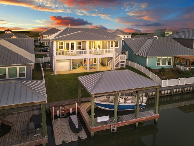 back of property featuring a patio area, a fenced backyard, a balcony, boat lift, and a yard