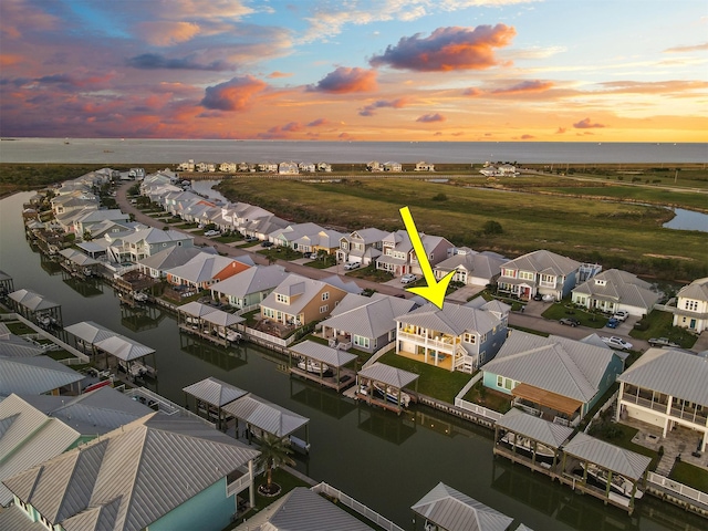aerial view at dusk featuring a residential view and a water view