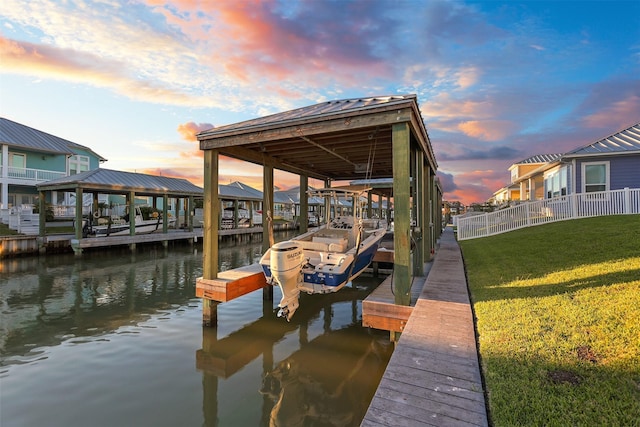 dock area featuring boat lift, a water view, and a yard