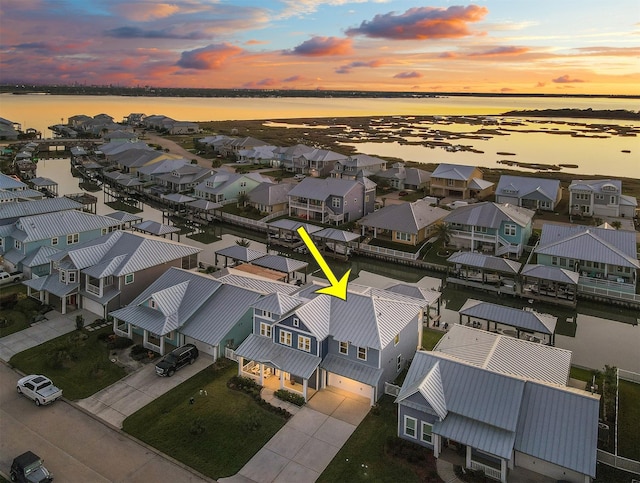 aerial view at dusk featuring a residential view and a water view