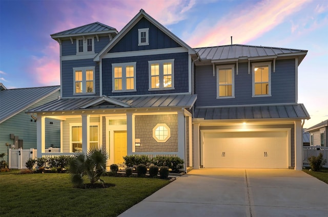 view of front of home with concrete driveway, a standing seam roof, an attached garage, and metal roof